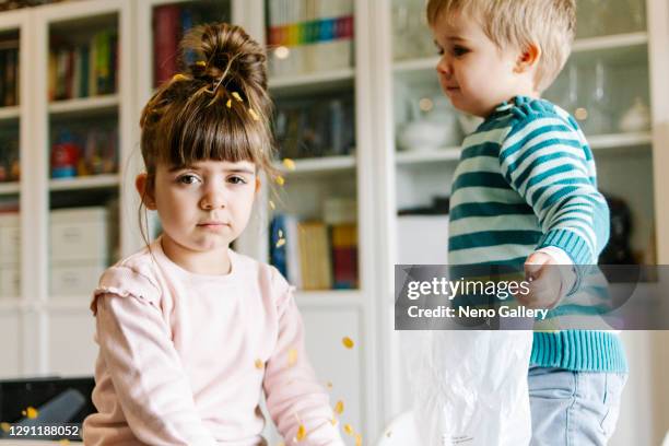 brother throwing cereal to his sister, who is resigned - boy eating cereal foto e immagini stock