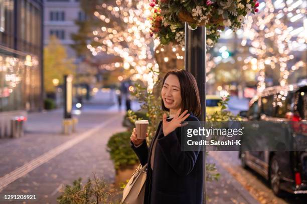 young woman seeing someone in city at christmas night - female waving on street stock pictures, royalty-free photos & images