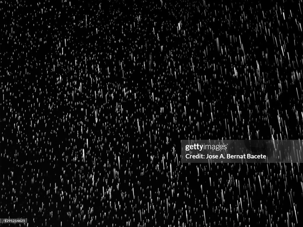 Full frame of raindrops falling on a black background.