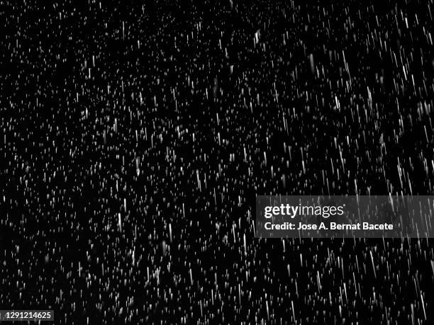 full frame of raindrops falling on a black background. - heavy rain stock pictures, royalty-free photos & images