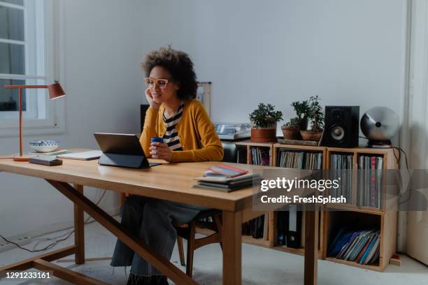 working from home late at night: a young african american woman sitting in her home office and using a digital tablet - office space movie stock pictures, royalty-free photos & images