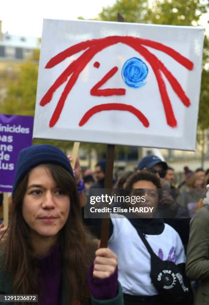 Femme tenant une pancarte avec un dessin d'un visage avec un oeil au beurre noir lors de la manifestation contre les violences faites aux femmes, le...