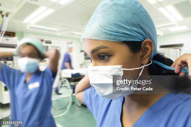 medical professionals putting on ppe - nurse tying mask stock pictures, royalty-free photos & images