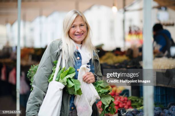 portrait of senior woman buying fruit and vegetables on outdoor martket. - greengrocer stock pictures, royalty-free photos & images