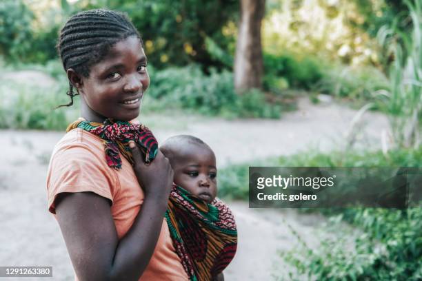 smiling young african mother with baby outdoors - malawi stock pictures, royalty-free photos & images