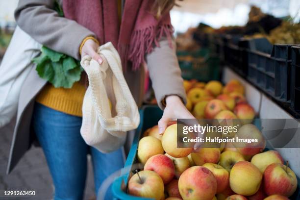unrecognizable young woman buying fruit on outdoor martket, looking at camera. - winter vegetables foto e immagini stock