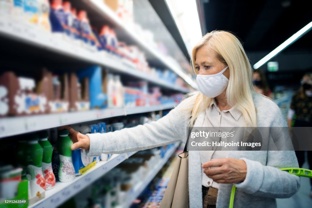 Senior woman with bag indoors doing shopping in store, coronavirus concept.