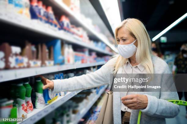 senior woman with bag indoors doing shopping in store, coronavirus concept. - supermarket mask stock pictures, royalty-free photos & images