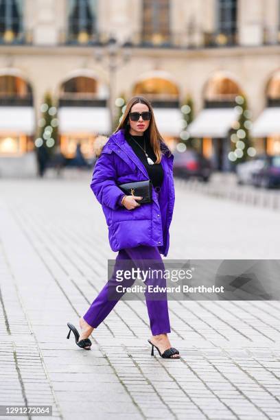 Maria Rosaria Rizzo wears sunglasses from Celine, a black pullover from Marella, a necklace from Le Carose, a purple oversized puffer winter jacket...
