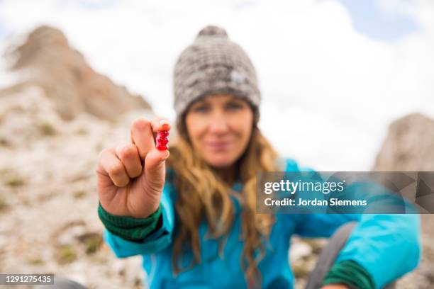 a woman holding out a gummy bear while hiking. - gummi bears stockfoto's en -beelden