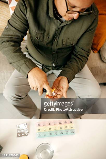 senior man organizing medication into pill dispenser - diabetes pills stock pictures, royalty-free photos & images