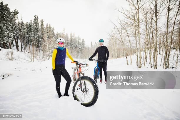 Portrait of smiling female friends on fat tire bike ride in snow covered forest