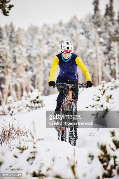 Smiling female cyclist riding fat tire bike on snowy trail on winter afternoon