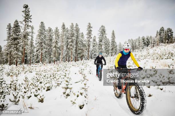 smiling female friends riding fat tire bikes on snow covered trail - seghet bildbanksfoton och bilder