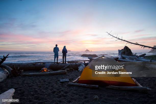 a couple backpacking and camping along washintons remote coast. - rialto beach fotografías e imágenes de stock