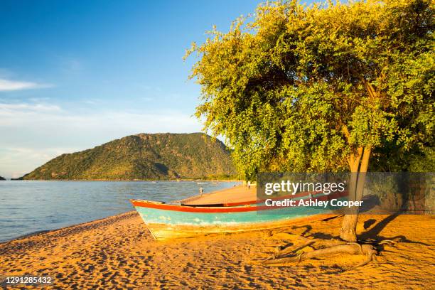 a boat on the beach at cape maclear on the shores of lake malawi, malawi, africa. - see lake malawi stock-fotos und bilder