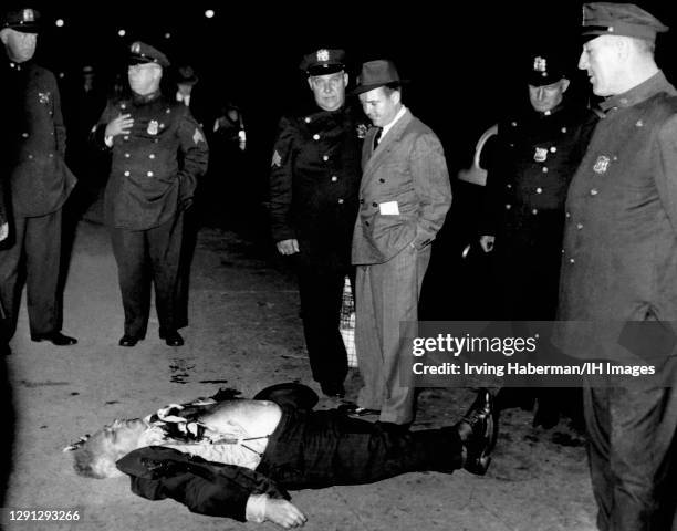 Brooklyn detectives and police officers inspect the wounds of the victim circa 1939 in Brooklyn, New York. Murder Inc. Is thought to have done the...