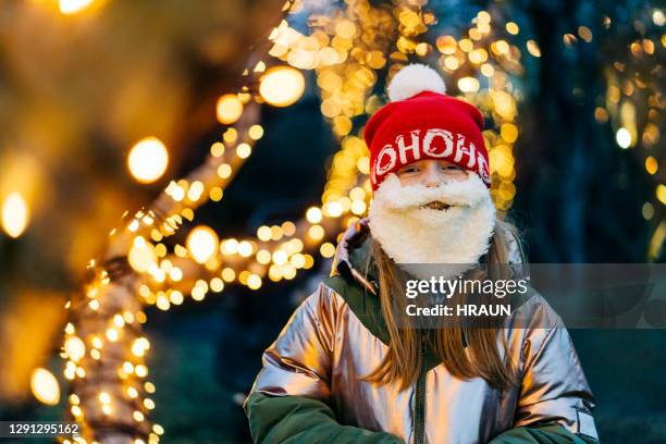 little girl wearing a santa hat and beard looking forward to christmas - santa hat and beard stock pictures, royalty-free photos & images