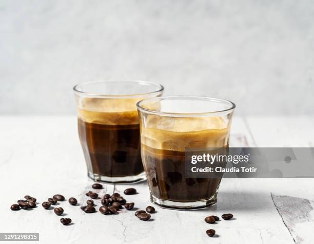 two shots of espresso on white, wooden background - espresso stockfoto's en -beelden