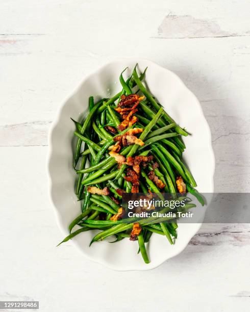 bowl of green beans with bacon on white, wooden background - green bean stockfoto's en -beelden