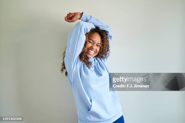 portrait of woman with curly hair in front of white wall - sweatshirt imagens e fotografias de stock