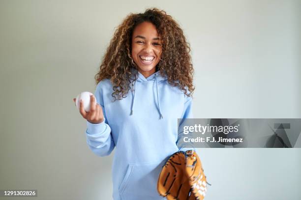 woman with ball and baseball glove in front of white wall - afro amerikanische kultur stock-fotos und bilder