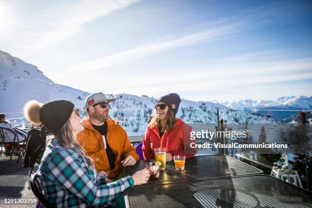 group of friends enjoying apres-ski at top of whistler mountain. - apres ski stock pictures, royalty-free photos & images