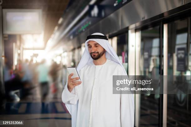 sjeik aan de telefoon in modern metrostation in dubai - dubai metro stockfoto's en -beelden