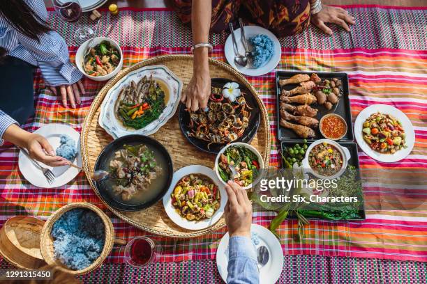 gruppe von asiatischen menschen familie genießen feiern thai essen abendessen, während auf der matte zu hause sitzen, nordost-thailand (issan) gesunde traditionelle thai-lebensmittel-konzept, top view - thailändische küche stock-fotos und bilder