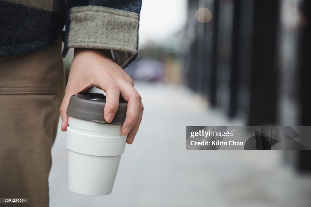 Asian woman walking with coffee in a reusable cup