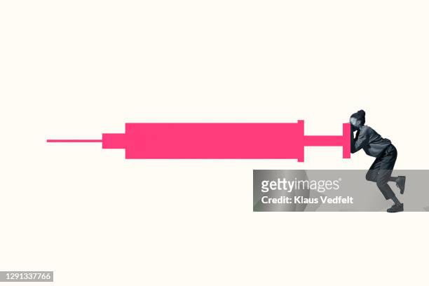 young woman hiding behind large pink injection - grande tablée photos et images de collection