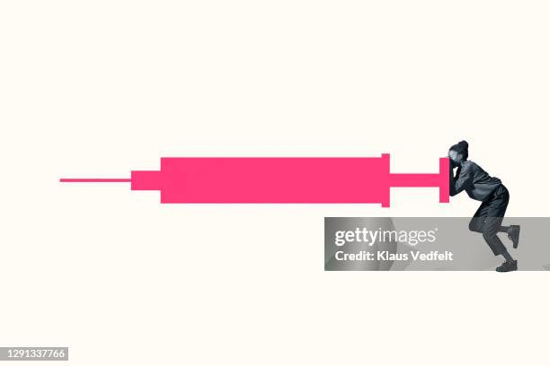 young woman hiding behind large pink injection - woman portrait studio shot stock pictures, royalty-free photos & images