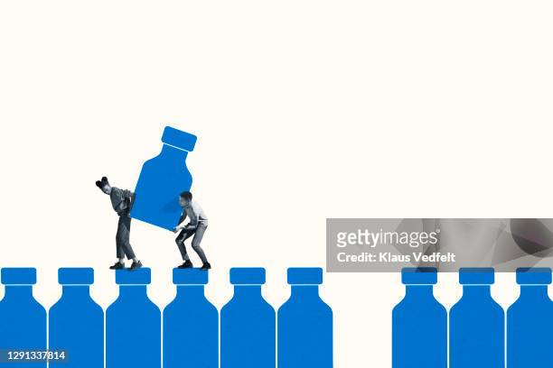 young man and woman carrying large blue vaccine bottle - man studio shot stock pictures, royalty-free photos & images