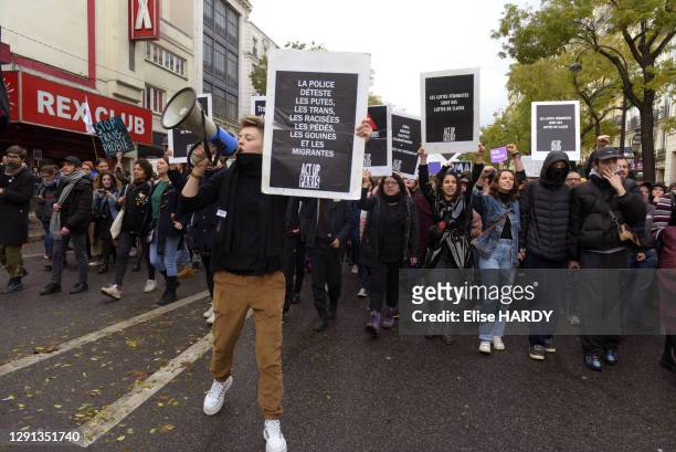 Homme du mouvement Act-Up tenant une pancarte avec slogan "La police déteste les putes, les trans, les racisées, les pédées, les gouines et les...