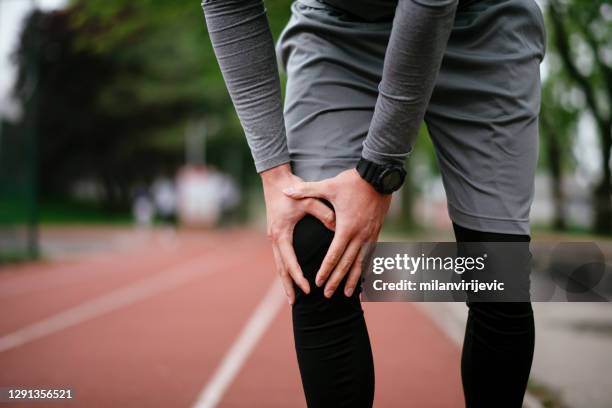 man has pain in the knee after run outdoors. - male knee stock pictures, royalty-free photos & images