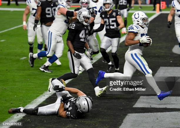 Running back Jonathan Taylor of the Indianapolis Colts scores on a 3-yard touchdown run against outside linebacker Cory Littleton and strong safety...