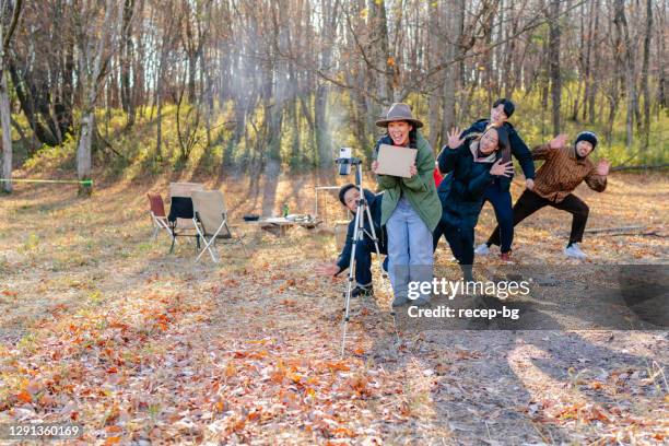 young woman vlogging with her friends at camp site in nature in winter - tripod stock pictures, royalty-free photos & images