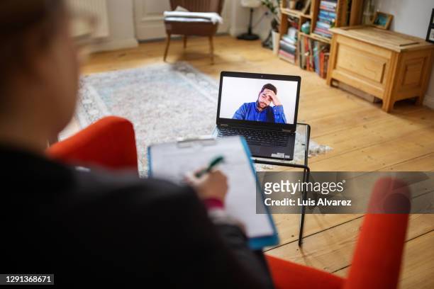 man having a cognitive behavioral therapy video call with mental health professional - alternative therapy stock pictures, royalty-free photos & images