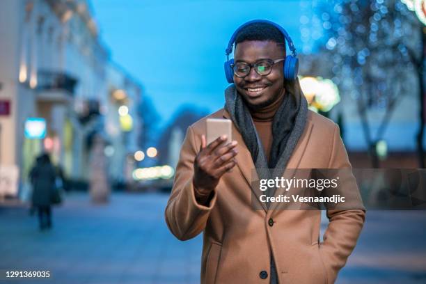 young man using smart phone at the street - winter coat stock pictures, royalty-free photos & images