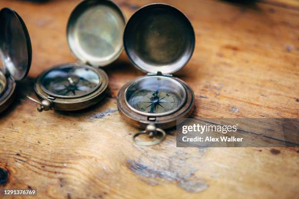 vintage metal compasses on a wooden table - pocket watch chains stock pictures, royalty-free photos & images