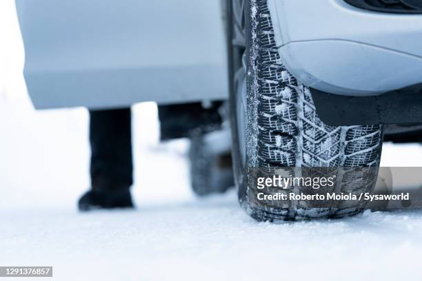 man getting out of car with winter tires in the snow - sel de voirie photos et images de collection