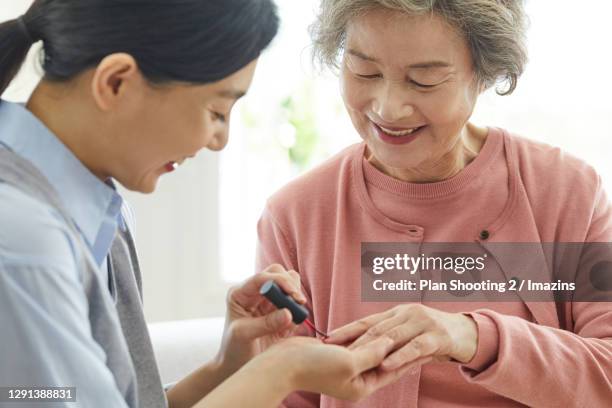 a nurse putting nail polish on old lady's hands - manicure stock pictures, royalty-free photos & images