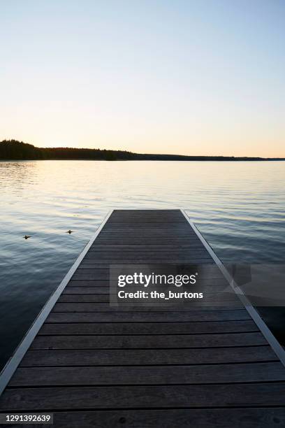 jetty at idyllic lake during sunset - ponton photos et images de collection