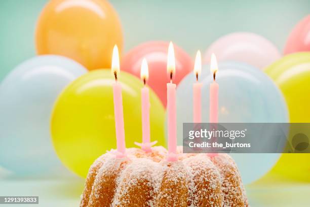 still life of birthday cake with pink candles and colourful balloons - cake candles stock pictures, royalty-free photos & images