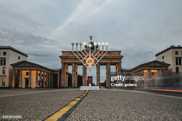 beleuchtetes menora-symbol vor brandenburger tor in berlin - judentum stock-fotos und bilder