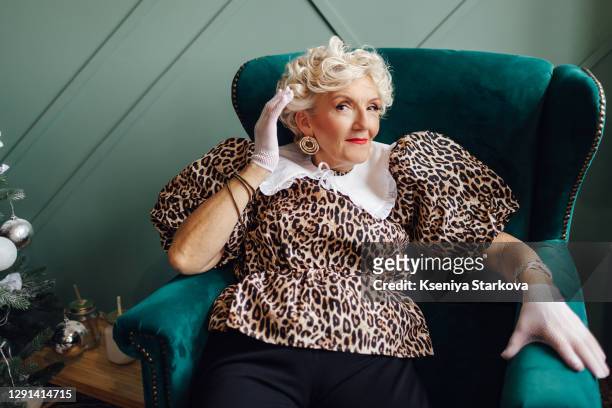 an old woman with short white curly hair sits in a blue armchair - art modeling studio stock-fotos und bilder