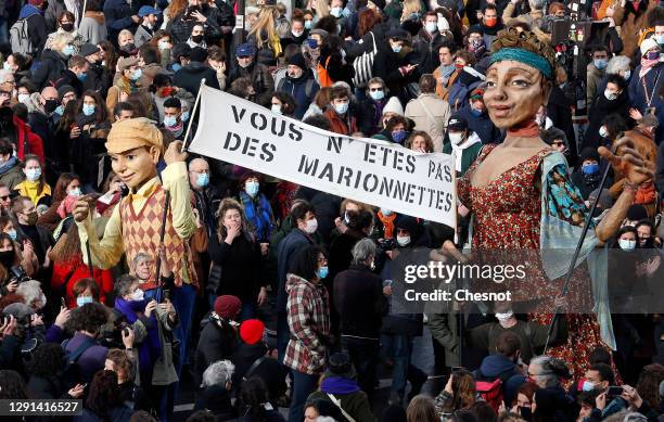 Giant puppets animated by comedians from the cultural sector hold a placard reading 'You are not puppets' as they participate to protest against the...