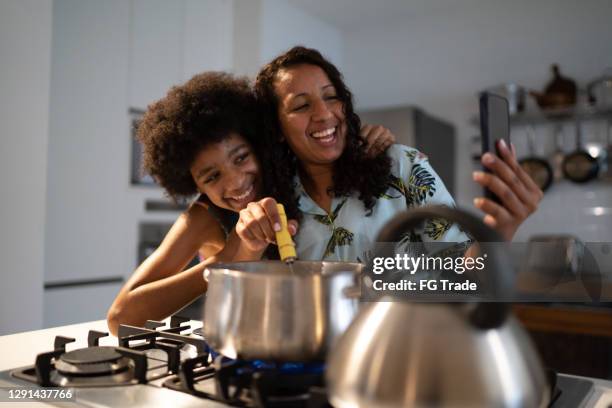 mãe e filha fazendo uma chamada de vídeo enquanto cozinhavam juntos em casa - mother daughter webcam - fotografias e filmes do acervo