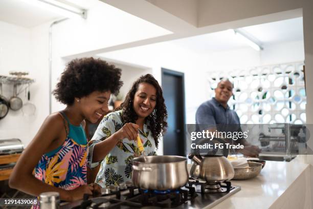 mutter und teenager tochter kochen zusammen zu hause - black mother and child cooking stock-fotos und bilder