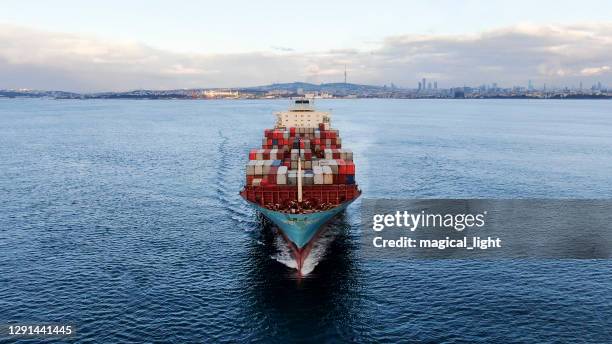 een groot schip dat talrijke vrachtcontainers door de baai van istanbul vervoert dat aan overzees weggaat. - bosporus shipping trade stockfoto's en -beelden